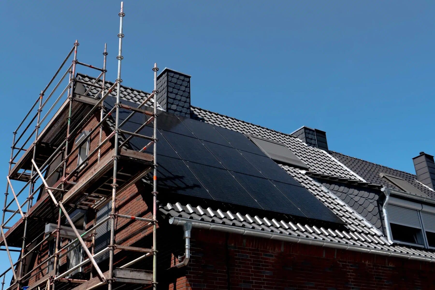 Eingerüstetes Klinkerhaus mit frisch belegter Photovoltaikanlage auf dem Dach